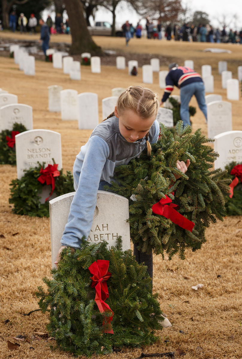 Staff photo by Doug Strickland / Ellie Appleby lays a wreathe on a grave at the Chattanooga National Cemetery on Saturday, Dec. 15, 2018, in Chattanooga, Tenn. Thousands of volunteers turned out to lay wreaths on graves at the cemetery which were donated by the Worcester Wreath Company through the Wreaths Across America program, which supplies wreaths to national cemeteries across the country.