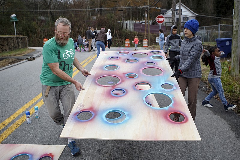 Aaron Cole, left, and Lauren Dunn move a stencil along Wilder Street on Sunday, Dec. 16, 2018 in Chattanooga, Tenn. Neighbors and volunteers from the American Institute of Architects, Chattanooga Design Studio, Range Projects and the Good Neighbor Network worked on the "tactical street painting project" on Wilder Street between North Chamberlain Avenue and Campbell Street. The project involved spray painting a dot pattern along Wilder Street. The purpose of the project is to help bring awareness to drivers that the road travels through a neighborhood with children and to get them to slow down. 