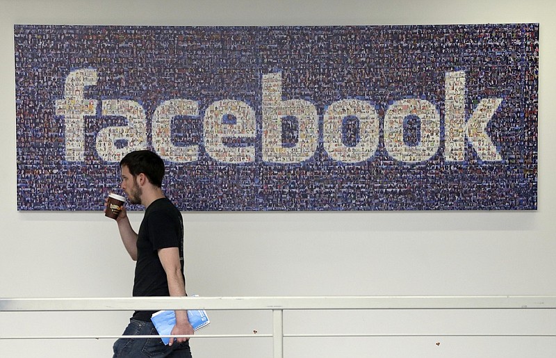 In this March 15, 2013, file photo, a man walks past a sign at Facebook headquarters in Menlo Park, California, USA. Facebook gave some companies more extensive access to users' personal data than it has previously revealed, letting them read private messages or see the names of friends without consent, according to a New York Times report published Wednesday Dec. 19, 2018. (AP Photo/Jeff Chiu, File)