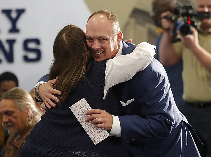 Georgia Tech football coach Geoff Collins gets a hug from a family member before speaking at his introductory news conference Dec. 7 in Atlanta.