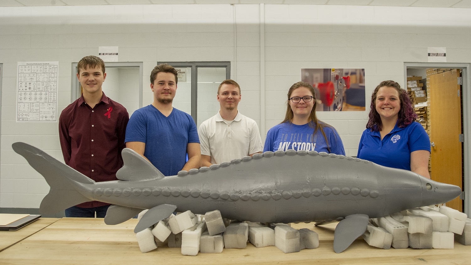 Dade County High School students Logan Gordy, Dakota Angle, and Taryn York (at left, second from left and second from right) pose with next to a model of a Lake Sturgeon they designed and 3-D printed for the Tennessee Aquarium Conservation Institute (TNACI). They are joined by TNACI Geographic Information Systems Analyst Sarah Sweat, at right, and their instructor, Nick Wilson, middle. Photo credit: Casey Phillips / Tennessee Aquarium. Contributed Photo/Times Free Press.
