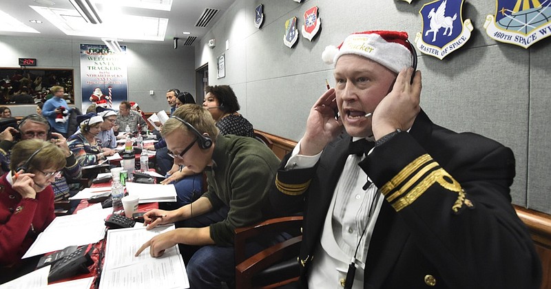 In this Dec. 24, 2017, file photo, Canadian Lt. Maj. Chris Hache takes a call while volunteering at the NORAD Tracks Santa center at Peterson Air Force Base in Colorado Springs, Colo. Hundreds of volunteers will help answer the phones again when the program resumes on Monday, Dec. 24, 2018, for the 63rd year. Children from around the world call to ask when Santa Claus will get to their house. (Jerilee Bennett/The Gazette via AP, File)