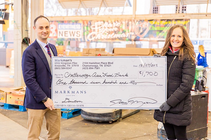 Jeff Markman, vice president of Markman's Chattanooga, donates $1,700 raised through its recent Vault Event Fundraiser, to the Chattanooga Area Food Bank. At right is Sarah Aligo, director of developmenfor the food bank.