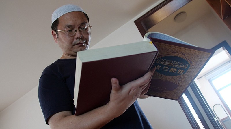 In this Sept. 28, 2018, photo, Muslim Chinese poet Cui Haoxin reads an Arabic prayer from a Quran in his home in the city of Jinan in China's eastern province of Shandong. Cui is an outspoken critic of the government's policies towards Muslims at home and abroad, writing poetry and tweeting about alleged abuses against Islamic traditions. (AP Photo/Sam McNeil)

