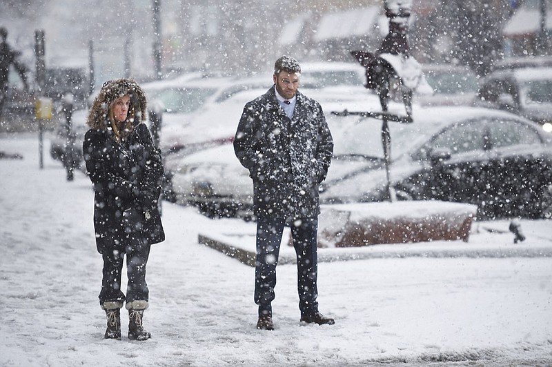 Patty Brennan and Matt Adamson wait to cross the street in the snow Thursday, Dec. 27, in Sioux Falls, S.D. More snow is expected to arrive in South Dakota on Thursday and Friday as a winter storm moves through the area. (Briana Sanchez/The Argus Leader via AP)

