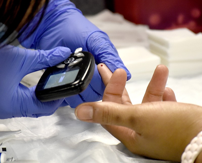 A nursing student takes the blood sugar reading from a health fair attendee at the 15th annual Hamilton County Minority Health Fair in 2017.
