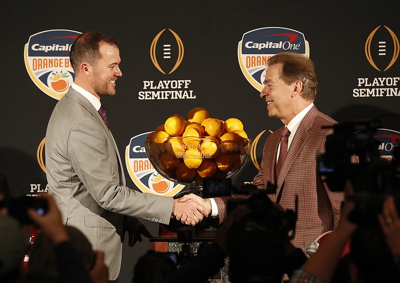 Oklahoma football coach Lincoln Riley, left, and Alabama's Nick Saban smile and shake hands during Friday's final news conference before tonight's Orange Bowl national semifinal.