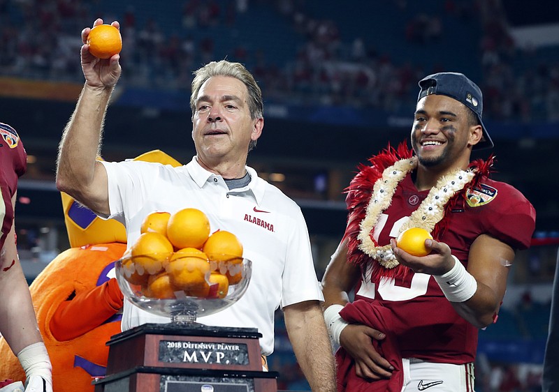 Alabama head coach Nick Saban and quarterback Tua Tagovailoa, throw oranges to the team during the Orange Bowl NCAA college football game trophy presentation, Sunday, Dec. 30, 2018, in Miami Gardens, Fla. Alabama defeated Oklahoma 45-34. (AP Photo/Wilfredo Lee)