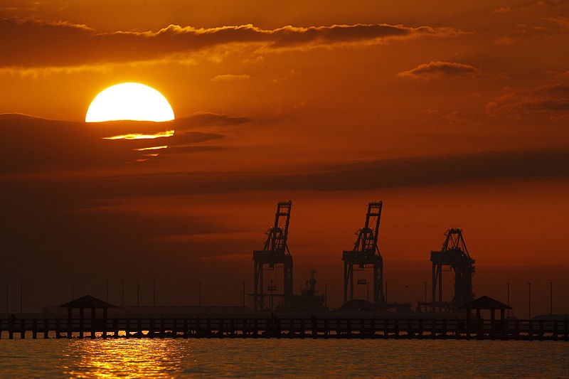 FILE- In this Dec. 2, 2018, file photo cranes at the Port of Gulfport are silhouetted by the setting sun at Gulfport, Miss. The Trump administration and China are facing growing pressure to blink in their six-month stare-down over trade because of jittery markets and portents of economic weakness. The longer their trade war lasts, the longer companies and consumers will feel the pain of higher-priced imports and exports. (AP Photo/Charlie Riedel, File)