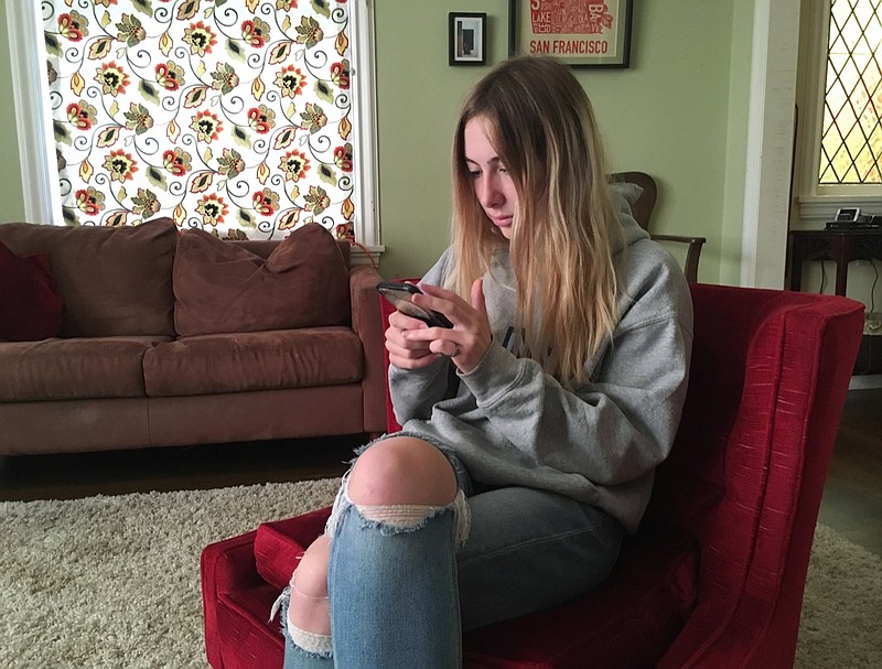 In this Nov. 1, 2018, photo, Laurel Foster holds her phone in San Francisco. Foster is among teens involved in Stanford University research testing whether smartphones can be used to help detect depression and potential self-harm. (AP Photo/Haven Daley)