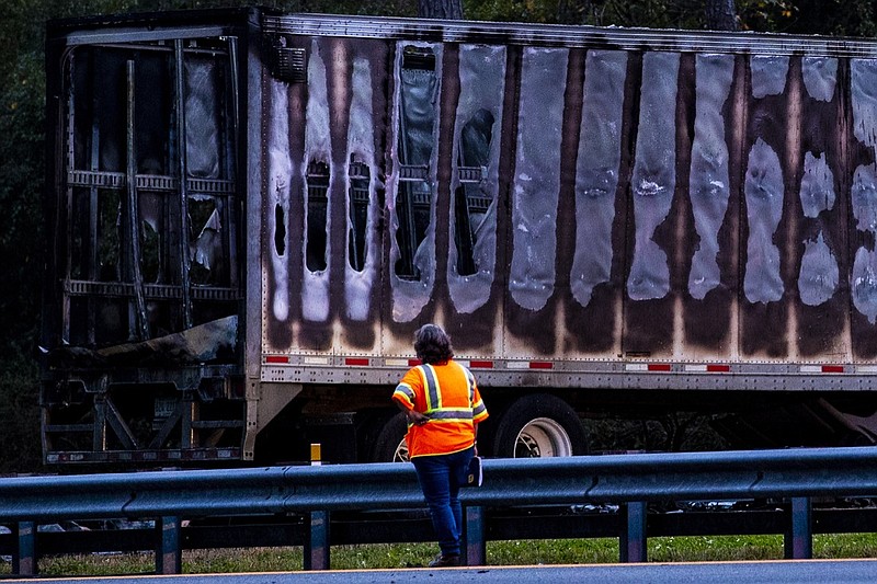 A worker looks at a charred semi-truck after a wreck with multiple fatalities on Interstate 75, south of Alachua, near Gainesville, Fla., Thursday, Jan. 3, 2019. Two big rigs and two passenger vehicles collided and spilled diesel fuel across the Florida highway Thursday, sparking a massive fire that killed several people, authorities said. (Lauren Bacho/The Gainesville Sun via AP)