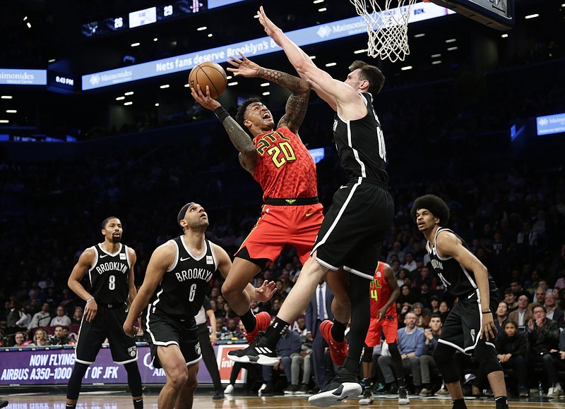 The Atlanta Hawks' John Collins (20) drives to the basket against the Brooklyn Nets' Rodions Kurucs during the first half of Wednesday night's game in Brooklyn, N.Y.