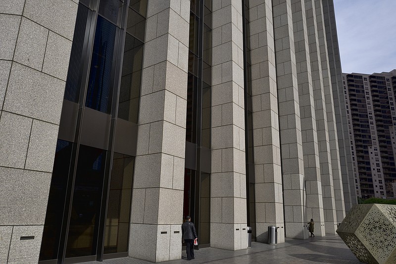 In this Jan. 8, 2019 photo people are towered by the front facade of the Bank of America Plaza Building in downtown Los Angeles. Companies are lining up to tell investors how much they made during the last three months of 2018, and the reports get going in earnest this upcoming week with Citigroup and a slew of other banks on deck. Expectations are high, and Wall Street is forecasting a fifth straight quarter where profit growth topped 10 percent for S&P 500 companies. Bank of America Corp. is expected to report financial earnings next week. (AP Photo/Richard Vogel)