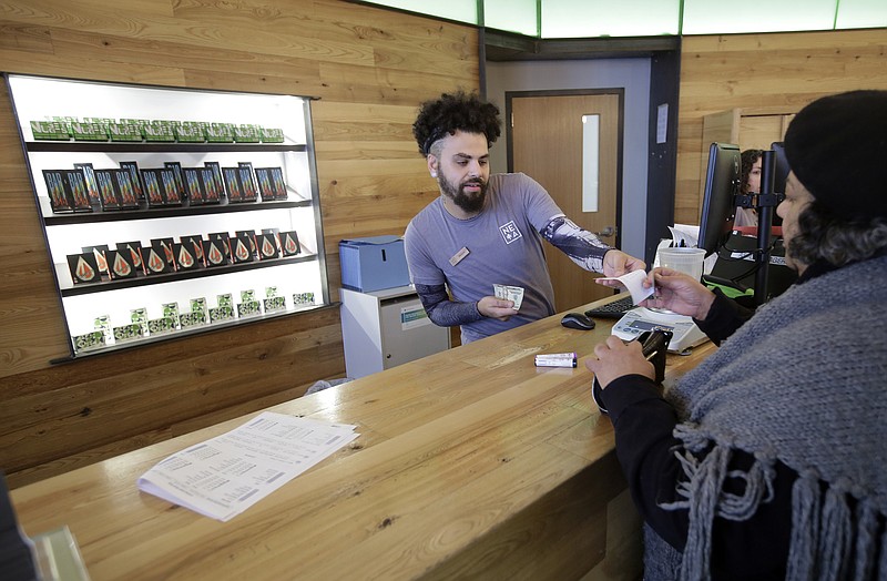 Patient service associate Nelson Rivera III, left, sells medical cannabis products to Victoria Silva, of Amherst, Massachusetts, at a New England Treatment Access medical marijuana dispensary, in Northampton, Mass.