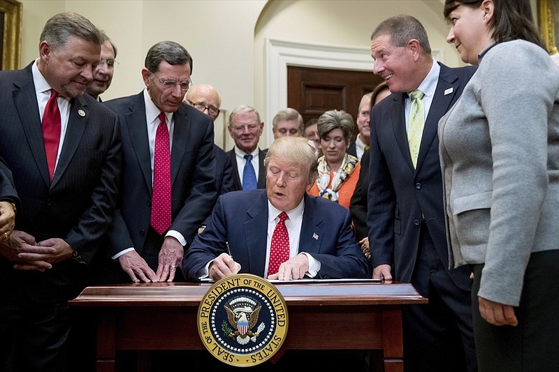 FILE - In this Tuesday, Feb. 28, 2017, file photo, President Donald Trump signs the Waters of the United States (WOTUS) executive order, in the Roosevelt Room in the White House in Washington, which directs the Environmental Protection Agency to withdraw the WOTUS rule, which expands the number of waterways that are federally protected under the Clean Water Act. Trump often points to farmers as among the biggest winners from the administration's proposed rollback of federal protections for wetlands and waterways across the country. But under longstanding federal law and rules, farmers and farm land already are exempt from most of the regulatory hurdles on behalf of wetlands that the Trump administration is targeting. (AP Photo/Andrew Harnik, File)

