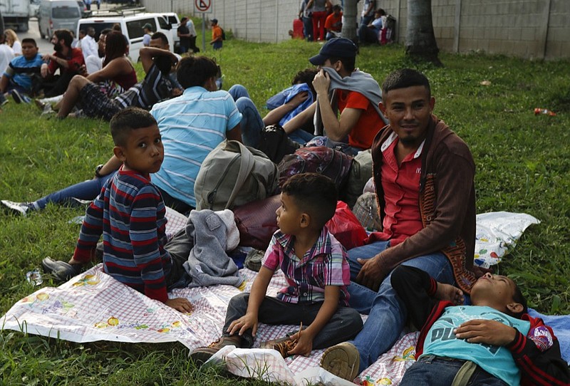 Freddy Rivas, second right, of Tocoa, Honduras, sits with his sons Josue, left, and Elkin, center, and his brother Mario, as they wait with scores of other migrants hoping to join a caravan to travel to the U.S. border, in San Pedro Sula, Honduras, Monday, Jan. 14, 2019. Hundreds of Hondurans hoping to reach the U.S. began gathering at a main bus station in San Pedro Sula Monday night to join a caravan that had been advertised in social media as departing in the early hours of Tuesday morning. (AP Photo/Delmer Martinez)

