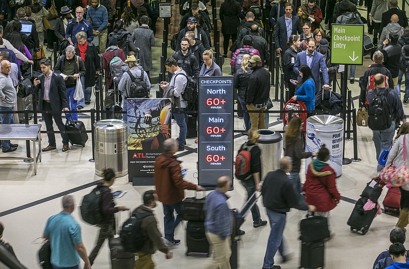 FILE- In this Monday, Jan. 14, 2019, file photo security lines at Hartsfield-Jackson International Airport in Atlanta stretch more than an hour long amid the partial federal shutdown, causing some travelers to miss flights. As the partial government shutdown moves through its fourth week with no end in sight, the economic blow is being felt not only by federal workers but also by business people, households and travelers across the country. (John Spink/Atlanta Journal-Constitution via AP, File)