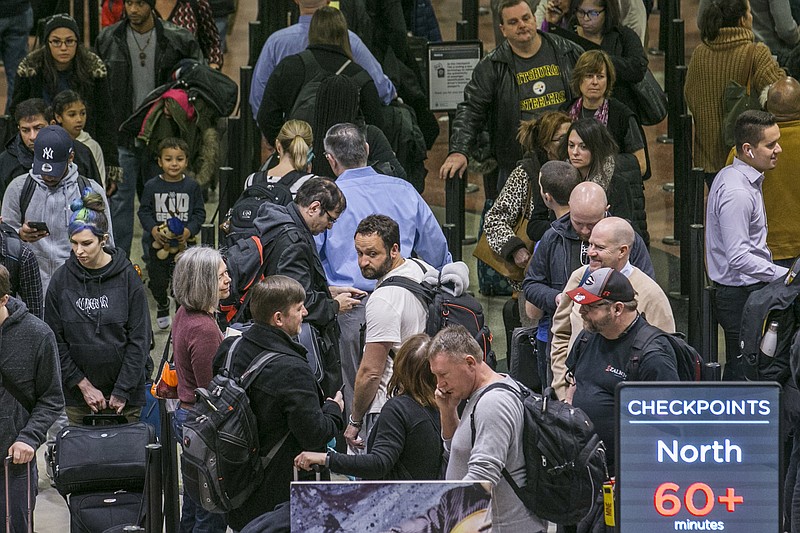 FILE- In this Monday, Jan. 14, 2019, file photo security lines at Hartsfield-Jackson International Airport in Atlanta stretch more than an hour long amid the partial federal shutdown. As the partial government shutdown moves through its fourth week with no end in sight, the economic blow is being felt not only by federal workers but also by business people, households and travelers across the country. (John Spink/Atlanta Journal-Constitution via AP, File)