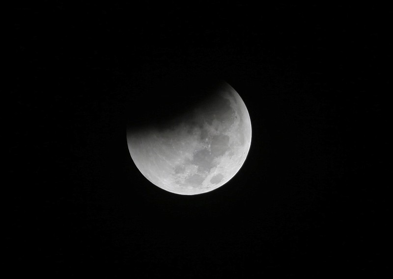 In this Saturday Aug. 28, 2018 file photo, Earth starts to cast its shadow on the moon during a complete lunar eclipse seen from Jakarta, Indonesia. Starting Sunday evening, Jan. 20, 2019, all of North and South America will be able to see the only total lunar eclipse of 2019 from start to finish this weekend. (AP Photo/Tatan Syuflana)