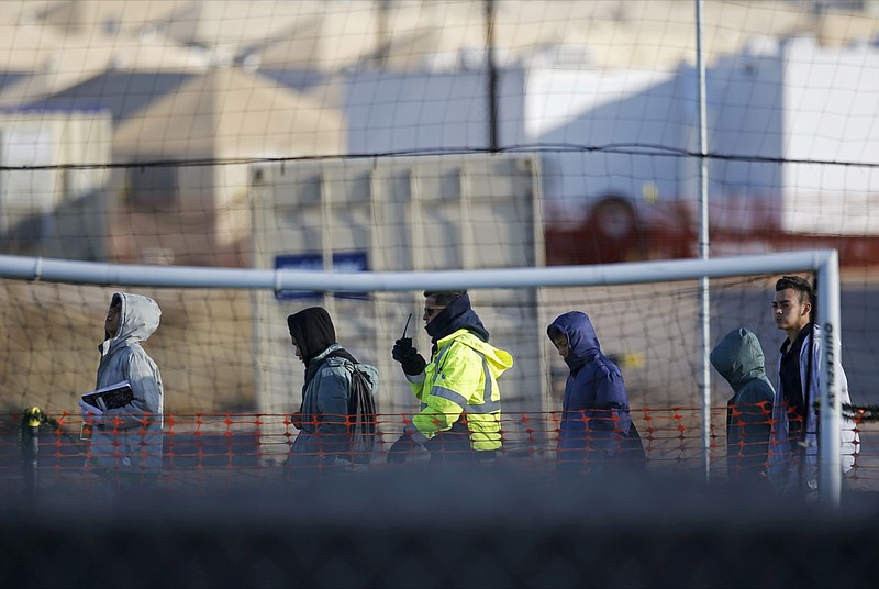 In this Dec. 13, 2018, file photo, teen migrants walk in line inside the Tornillo detention camp in Tornillo, Texas. Government investigators say many more migrant children may have been separated from their parents than the Trump administration has acknowledged. (AP Photo/Andres Leighton, File)