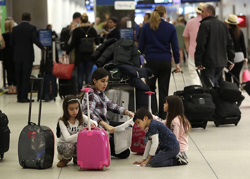 Travelers organize their luggage before entering a security checkpoint at Miami International Airport, Friday, Jan. 18, 2019, in Miami. The three-day holiday weekend is likely to bring bigger airport crowds. (AP Photo/Lynne Sladky)