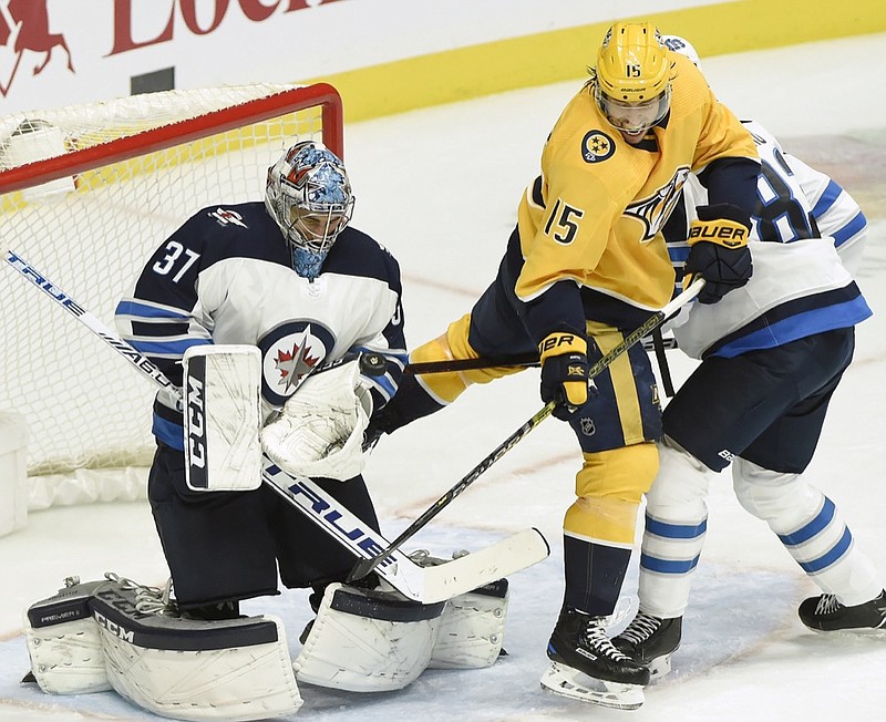 Winnipeg Jets goaltender Connor Hellebuyck (37) stops a shot as Nashville Predators right wing Craig Smith (15) looks for a rebound during the second period of an NHL hockey game Thursday, Jan. 17, 2019, in Nashville, Tenn. (AP Photo/Mark Zaleski)

