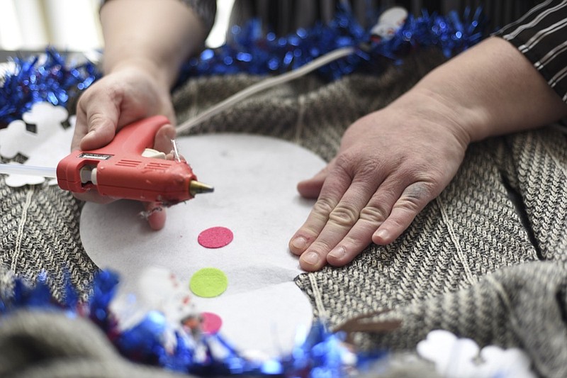 Doris Cochran works on "an ugly sweater," which she is planning to sell, Friday, Jan. 18, 2019 in her apartment in Arlington, Va., Cochran is a disabled mother of two young boys living in subsidized housing in Arlington, Virginia. She's stockpiling canned foods to try to make sure her family won't go hungry if her food stamps run out. She says she just doesn't know "what's going to happen" and that's what scares her the most. (AP Photo/Sait Serkan Gurbuz)

