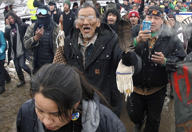 FILE - In this Feb. 22, 2017, file photo, a large crowd representing a majority of the remaining Dakota Access Pipeline protesters, including Nathan Phillips, center with glasses, march out of the Oceti Sakowin camp before the deadline set for evacuation of the camp near Cannon Ball, N.D. Phillips says he felt compelled to get between a group of black religious activists and largely white students with his ceremonial drum to defuse a potentially dangerous situation at a rally in Washington. (Mike McCleary/The Bismarck Tribune via AP, File)


