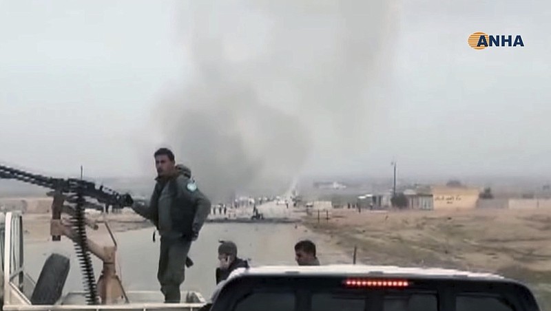 This frame grab from video provided by Hawar News, ANHA, the news agency for the semi-autonomous Kurdish areas in Syria, shows Kurdish fighters standing guard at the site of a suicide attack near the town of Shaddadeh, in Syria's northeastern province of Hassakeh, Syria, Monday, Jan. 21, 2019. The state news agency SANA and the Kurdish Hawar news agency, said that the blast was a suicide bombing that targeted a Syrian Kurdish checkpoint. (ANHA via AP)

