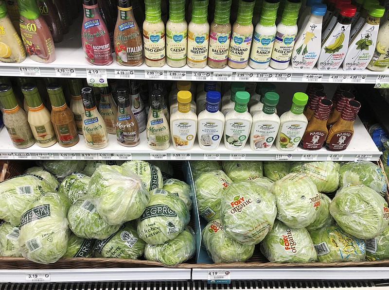 In this Monday, Jan. 21, 2019, photo, regular iceberg lettuce, lower left, selling at $3.19 each, is displayed next to organic iceberg lettuce selling at $4.19 each, at a grocery store in North Miami, Fla. U.S. shoppers are still paying more for organic food, but the price premium is falling as organic options multiply. (AP Photo/Wilfredo Lee)