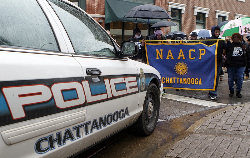 Staff photo by C.B. Schmelter / The NAACP march against police brutality and excessive force turns off of East 7th Street onto Market Street and past a Chattanooga Police car helping block off their route on Wednesday.