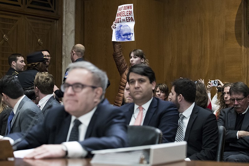 An environmental protester holds a sign during the Senate Committee on Environment and Public Works' confirmation hearing earlier this month for Andrew Wheeler, President Donald Trump's nominee to lead the Environmental Protection Agency. (Sarah Silbiger/The New York Times)