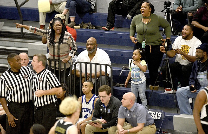 Some fans make their opinions known as officials, left, discuss a change of possession during a boys' high school basketball game between Lookout Valley and Arts and Sciences last Friday night.