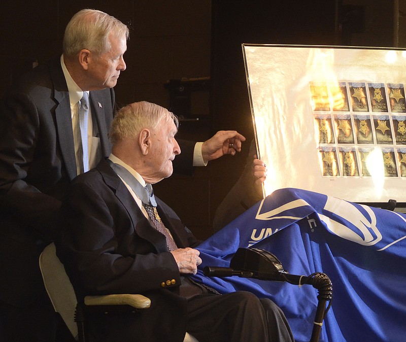 Charles Coolidge, seated at right, unveils a commemorative stamp honoring Medal of Honor recipients during a Wednesday ceremony at the Signal Crest United Methodist Church. Helping him is Charlie Coolidge.