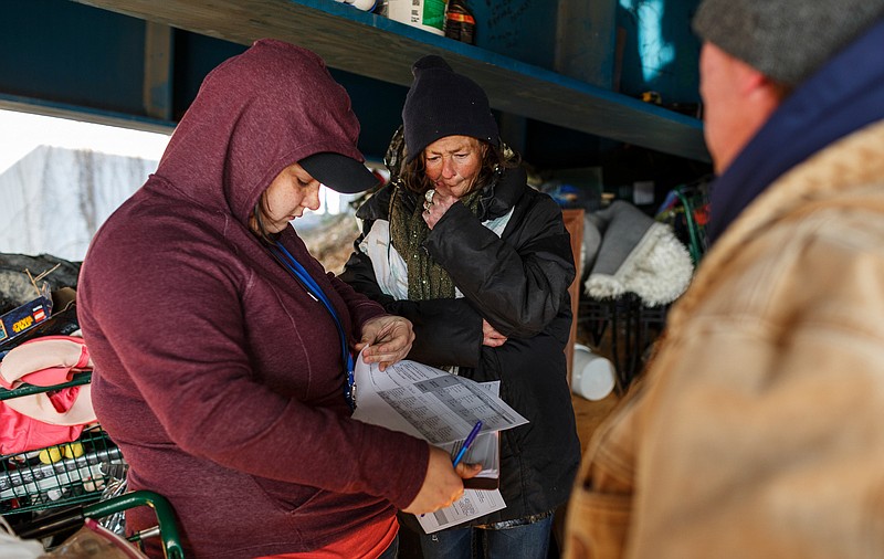 Lauren DeLaPaz, left, asks Laura K. a series of survey questions at her camp beneath an overpass while conducting an annual Point In Time Count of the city's homeless population on Friday, Jan. 25, 2019, in Chattanooga, Tenn. Service providers and volunteers conducted the PIT count, which surveys individuals experiencing homelessness in order to better target services to meet their needs, on Thursday night and Friday morning.