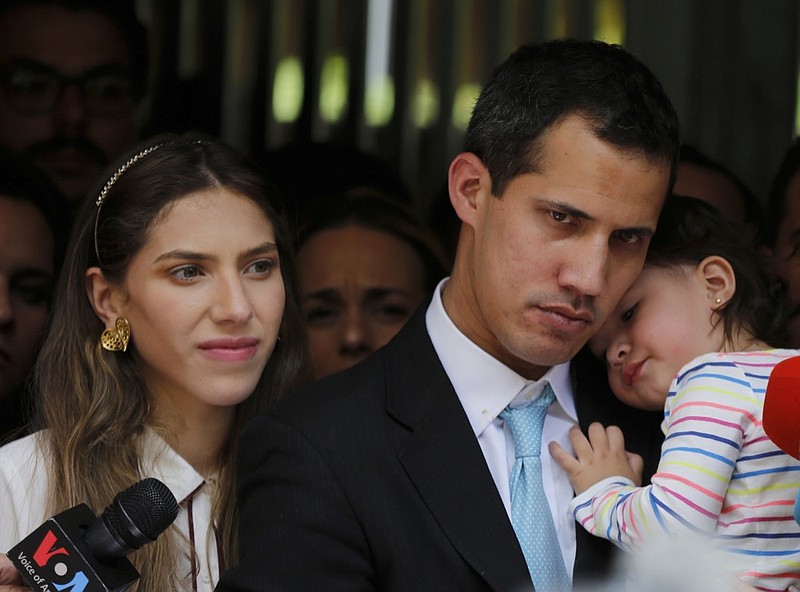 Opposition National Assembly President Juan Guaido, accompanied by his wife Fabiana Rosales and his 20-month-old daughter Miranda, listens to a reporter's question during a news conference outside their apartment, in Caracas, Venezuela, Thursday, Jan. 31, 2019. Guaido said security forces showed up at their home in an attempt to intimidate him. "The dictatorship thinks it can intimidate us," Guaido said. (AP Photo/Fernando Llano)

