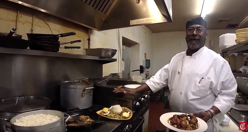 Chef Neville with a plate of wings and Mrs. B's voodoo chicken.