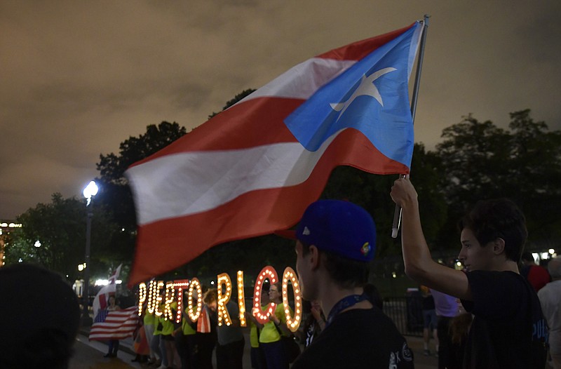FILE - In this Sept. 20, 2018 file photo, people gather outside the White House in Washington, during a vigil commemorating the one-year anniversary of Hurricane Maria hitting Puerto Rico. A federal bankruptcy judge on Monday, Feb. 4, 2019 approved a major debt restructuring plan for Puerto Rico in the first deal of its kind for the U.S. territory since the government declared nearly three years ago that it was unable to pay its public debt. (AP Photo/Susan Walsh, File)