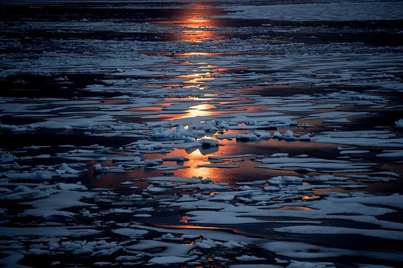 FILE- In this July 23, 2017, file photo the midnight sun shines across sea ice along the Northwest Passage in the Canadian Arctic Archipelago. The magnetic north pole is wandering about 34 miles (55 kilometers) a year. At the end of 2017 it crossed the international date line. That means it's not even the same day at the new magnetic north pole as it is at the spot of 2010's magnetic north pole. It's leaving the Canadian Arctic on its way to Siberia. (AP Photo/David Goldman, File)

