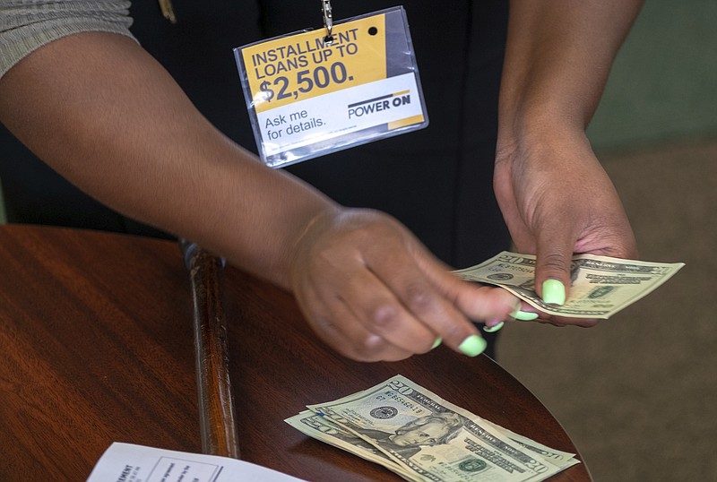 FILE- In this Aug. 9, 2018, photo a manager of a financial services store in Ballwin, Mo., counts cash being paid to a client as part of a loan. The nation's federal financial watchdog has announced its plans to roll back most of its consumer protections governing the payday lending industry. It's the Consumer Financial Protection Bureau's first rollback of regulations under its new Director, Kathy Kraninger, who took over the bureau late last year. (AP Photo/Sid Hastings, File)