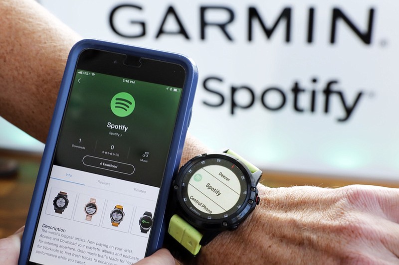 FILE- In this Oct. 3, 2018, file photo a Garmin International employee shows the new Spotify app on his smartphone integrated with his Garmin fenix 5 Plus watch during a presentation in New York. Spotify reports financial results Wednesday, Feb. 6, 2019. (AP Photo/Richard Drew, File)

