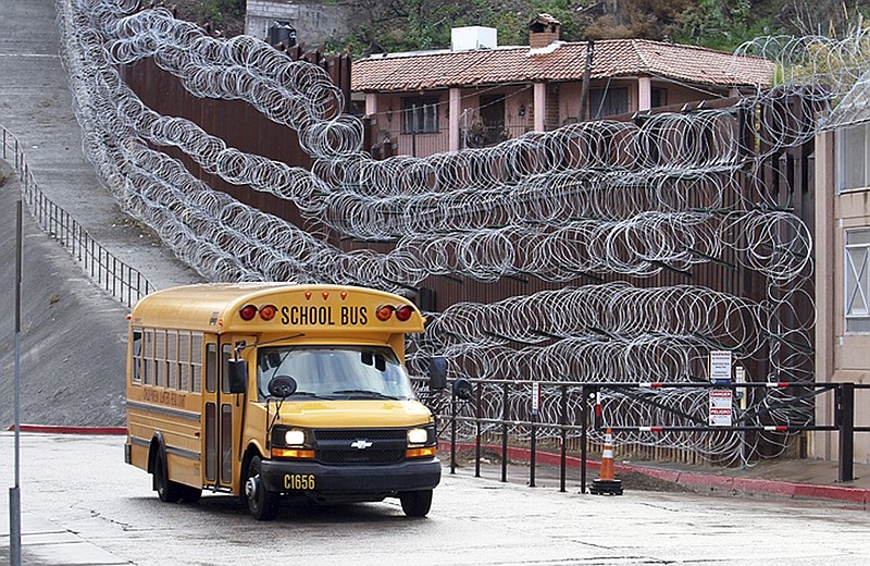 In this Monday, Feb. 4, 2019 photo, a school bus rolls past the concertina wire-covered fence at East International and Nelson Streets in downtown Nogales, Ariz. The small Arizona border city is fighting back against the installation of razor fencing that now covers the entirety of a tall border fence along the city's downtown area. The city of Nogales, which sits on the border with Nogales, Mexico, is contemplating a proclamation Wednesday, Feb. 6, 2019, condemning the use of concertina wire in its town. (Jonathan Clark/Nogales International via AP)

