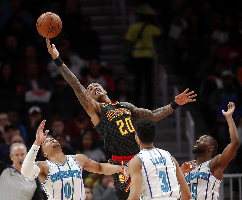 Atlanta Hawks forward John Collins (20) grabs a rebound against the Charlotte Hornets' Miles Bridges (0), Jeremy Lamb (3) and Kemba Walker (15) during the second half of Saturday night's game in Atlanta. Charlotte won 129-120.