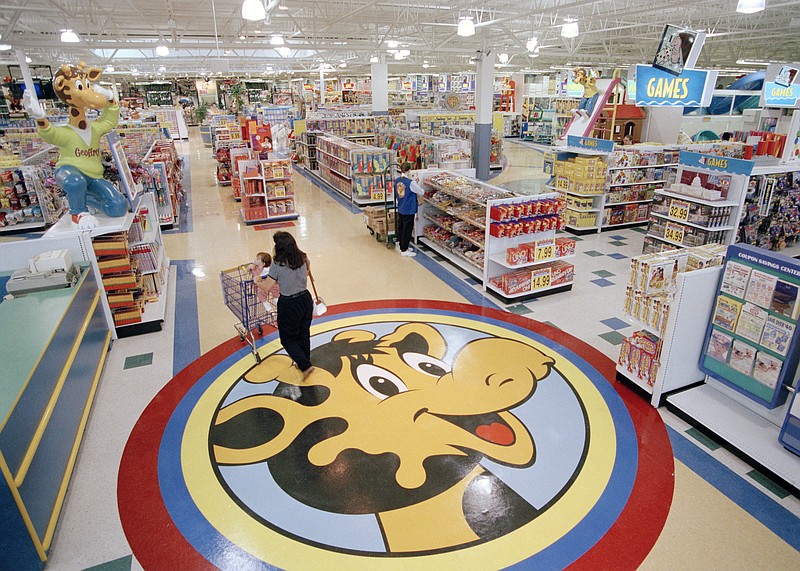 FILE- In this July 30, 1996, file photo, a woman pushes a shopping cart over a graphic of Toys R Us mascot Geoffrey the giraffe at the Toys R Us store in Raritan, N.J. Richard Barry, a former Toys R Us executive and now CEO of the new company called Tru Kids Inc., is exploring freestanding stores, shops within existing stores as well as e-commerce. Tru Kids, owned by former investors of Toys R Us, will manage the Toys R Us, Babies R Us and Geoffrey brands.s. (AP Photo/Daniel Hulshizer, File)