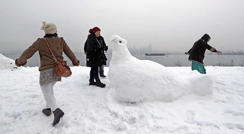 Antoniette Richards, left, and her friends Zusette Rios, center, of Dallas, and Sister Monyen, of the Philippines, explore near a nearly life-sized snow sculpture of a sea lion Monday, Feb. 11, 2019, in Seattle. Schools and universities closed across Washington state and the Legislature cancelled all hearings as the Northwest dealt with snow and ice and prepared for more as a series of winter storms socked the region. (AP Photo/Elaine Thompson)

