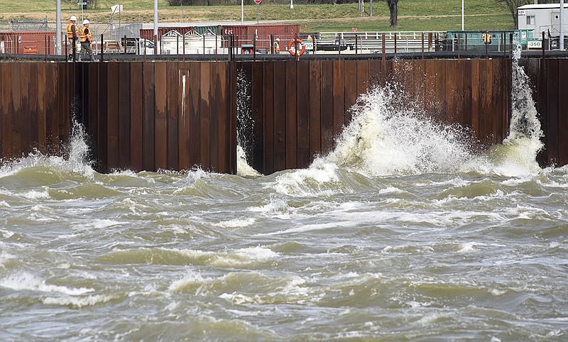 Workmen keep an eye on water crashing into the coffer dam below Chickamauga Dam Thursday as the Tennessee Valley Authority moves large quantities of lake water through the spillways.

