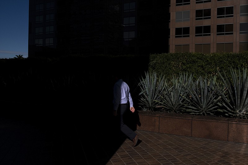FILE- In this Dec. 4, 2018, file photo a man walks into the shade of a building in downtown Los Angeles. When deciding whether to buy, skip or toss an item, minimalists try to determine whether it adds value to their lives. Apply minimalism to your financial life, and you can shed outdated obligations and reduce stress. (AP Photo/Jae C. Hong, File)