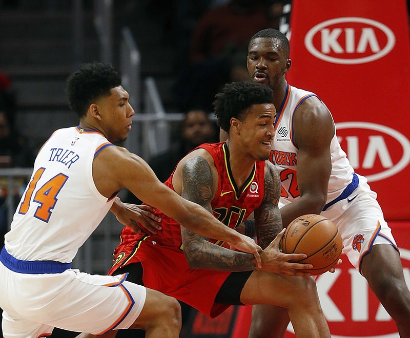 Atlanta Hawks forward John Collins tries to go between New York Knicks guard Allonzo Trier and forward Noah Vonleh during the second half of Thursday night's game in Atlanta.