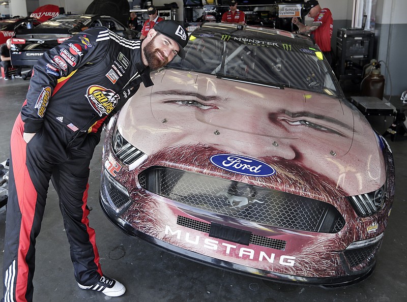 AP photo / NASCAR driver Corey LaJoie leans over the hood of his race car with a likeness of him painted on the front end before a practice session in February at Daytona International Speedway.