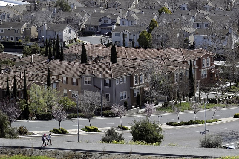 FILE - In this March 6, 2018, file photo, people walk along a path in front of a row of homes in San Jose, Calif. (AP Photo/Marcio Jose Sanchez, File)

